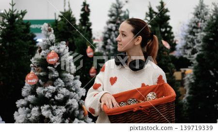 A store sells Christmas decorations. A young girl is choosing decorations for the Christmas celebration. A store sells Christmas decorations. A young girl is choosing decorations for the Christmas celebration. 139719339