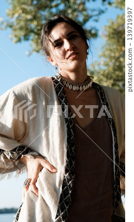 A beautiful brunette dressed in boho style meditates and dances in the forest. A magical ritual takes place against a green forest backdrop. A beautiful brunette dressed in boho style meditates and dances in the forest. A magical ritual takes place against a green forest backdrop. 139719397