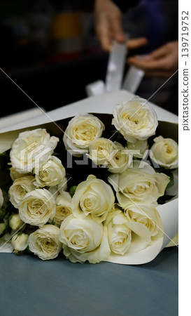 Beautiful white roses in a flower shop. Florist assembles a bouquet to order 139719752