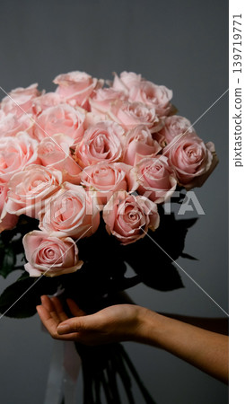 A florist creates a custom bouquet. Close-up of a bouquet of roses against a gray background. Beautiful pink roses at a flower shop. A florist creates a custom bouquet. Close-up of a bouquet of roses against a gray background. Beautiful pink roses at a flower shop. 139719771