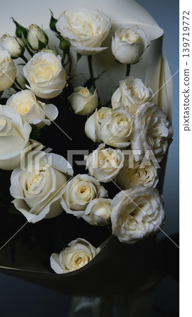 Beautiful white roses in a flower shop. Florist assembles a bouquet to order Beautiful white roses in a flower shop. Florist assembles a bouquet to order 139719772