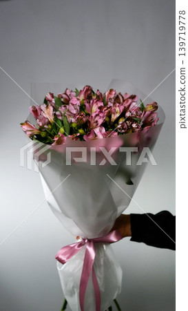 Female florist arranges delicate bouquet of pink alstroemeria flowers. Flower delivery. Small business concept Female florist arranges delicate bouquet of pink alstroemeria flowers. Flower delivery. Small business concept 139719778