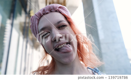 A teenage girl poses for a selfie on her smartphone. She shows her pierced tongue to her friends A teenage girl poses for a selfie on her smartphone. She shows her pierced tongue to her friends 139719786
