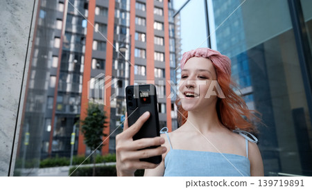 A teenage girl poses and smiles for a selfie on a smartphone. A teenage girl poses and smiles for a selfie on a smartphone. 139719891