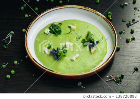 Vibrant green pea soup on dark surface, styled for gourmet food photography Vibrant green pea soup on dark surface, styled for gourmet food photography 139720898