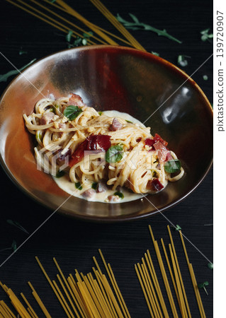 Delicious pasta dish in a wooden bowl, garnished with greens and red tomatoes 139720907