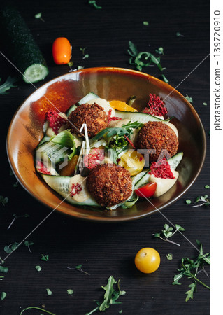 Falafel salad bowl with fresh vegetables and herbs on dark wooden background Falafel salad bowl with fresh vegetables and herbs on dark wooden background 139720910