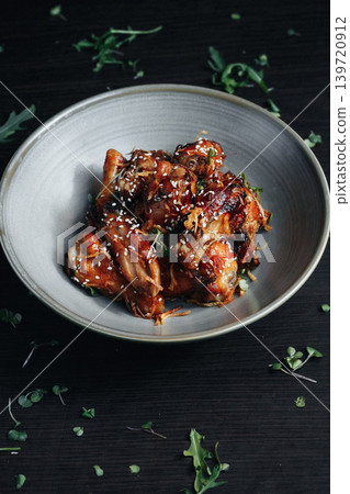 Richly glazed chicken served in a modern gray bowl with fresh herbs on a dark wo Richly glazed chicken served in a modern gray bowl with fresh herbs on a dark wo 139720912