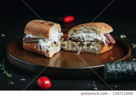 Tasty sandwich cut in half on a rustic plate with cherry tomatoes Tasty sandwich cut in half on a rustic plate with cherry tomatoes 139721000