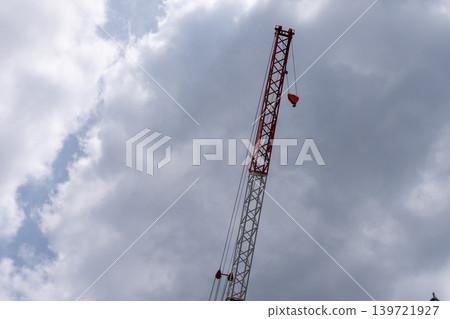 紅白相間的建築起重機在陰雲密佈的天空中聳立。 紅白相間的建築起重機在陰雲密佈的天空中聳立。 139721927