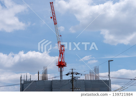 一座紅白相間的建築起重機，背景是藍天白雲。 139721984