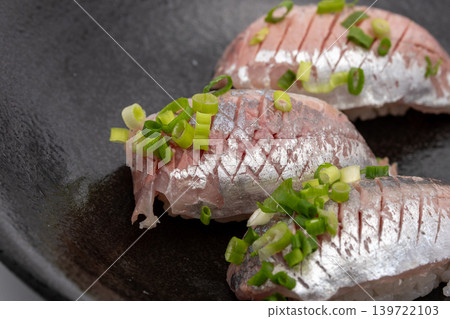 Close-up of a blue fish nigiri sushi topped with green onions. Close-up of a blue fish nigiri sushi topped with green onions. 139722103