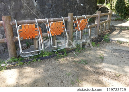 一張照片顯示,公園裡排列著一排橘色的折疊椅。 一張照片顯示,公園裡排列著一排橘色的折疊椅。 139722729