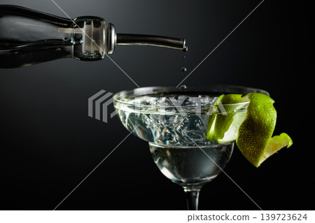 Vodka or gin is poured into a glass with ice. Vodka or gin is poured into a glass with ice. 139723624