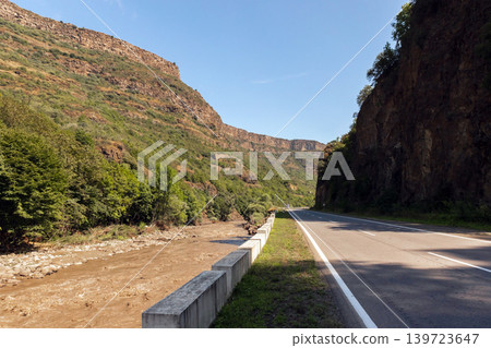 A scenic mountain road runs beside a muddy river through a rocky canyon, Armenia A scenic mountain road runs beside a muddy river through a rocky canyon, Armenia 139723647