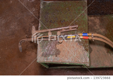 Vintage Gas Welding Torch with Red and Blue Hoses on Metal Bench Vintage Gas Welding Torch with Red and Blue Hoses on Metal Bench 139723668