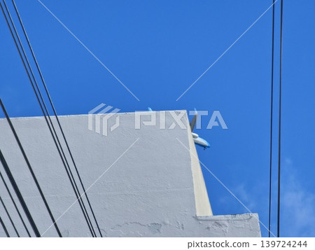 Airplane partially hidden behind urban building against blue sky in Cordoba 139724244