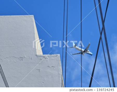 Jet aircraft crossing cloudy sky above utility cables in Cofico district Cordoba Jet aircraft crossing cloudy sky above utility cables in Cofico district Cordoba 139724245