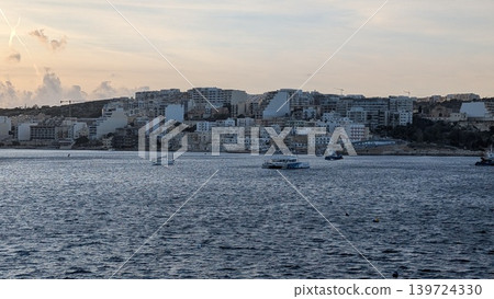 Evening view at St. Paul's bay with boats sailing and buildings on the island Evening view at St. Paul's bay with boats sailing and buildings on the island 139724330
