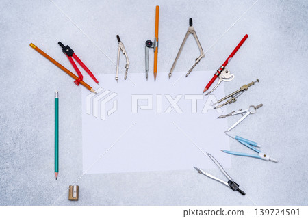 Drawing compass Tools Supplies arranged around Paper copy space. Stationery for school or engineering table top view Drawing compass Tools Supplies arranged around Paper copy space. Stationery for school or engineering table top view 139724501