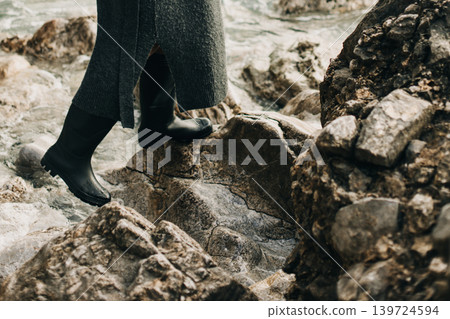 Girl in rubber boots on the rocks by the sea. Girl in rubber boots on the rocks by the sea. 139724594