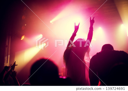 Rock, concert and people dance at night, event or party at music festival with fans in audience at stage. Crowd, energy and woman with hands in sign for metal, sound or social celebration at rave Rock, concert and people dance at night, event or party at music festival with fans in audience at stage. Crowd, energy and woman with hands in sign for metal, sound or social celebration at rave 139724691