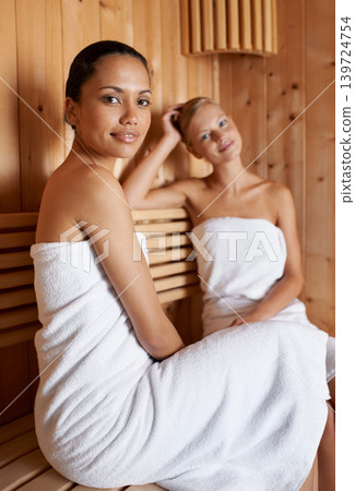 Sauna, portrait and friends relax in spa for skincare, healthy detox or sweat for beauty wellness. Luxury, treatment and women sitting with towel in steam room for calm, skin care or benefits to body 139724754