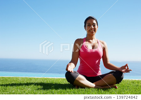 Grass, yoga and portrait of woman in lotus pose by water for holistic balance, mindfulness and exercise. Meditating, hands in prayer and person by ocean for wellness, health and zen energy outdoors Grass, yoga and portrait of woman in lotus pose by water for holistic balance, mindfulness and exercise. Meditating, hands in prayer and person by ocean for wellness, health and zen energy outdoors 139724842