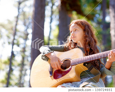 Nature, camp and girl kid with guitar for entertainment, talent or music in woods or forest. Playing, musician and child with acoustic string instrument outdoor in park or field on weekend trip. 139724931