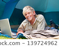 Child, boy and happy with laptop in tent for camping, social media and online movie with portrait in nature. Person, face and kid with smile outdoor on grass for gaming, vacation and holiday fun 139724962