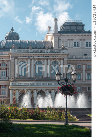 Sunlit opera house behind fountain with blue sky Sunlit opera house behind fountain with blue sky 139725434