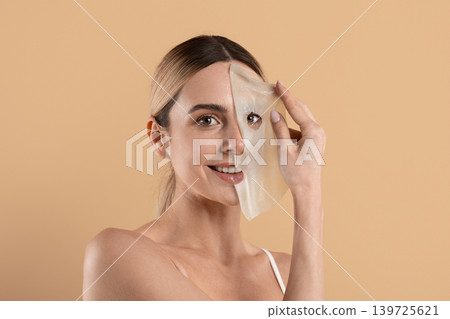 Young woman removing peel off facial mask during skincare treatment Young woman removing peel off facial mask during skincare treatment 139725621