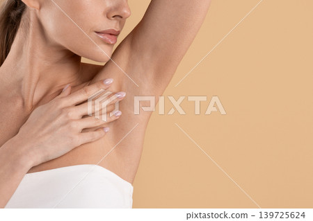 Young woman raising arm to show smooth clean underarm skin Young woman raising arm to show smooth clean underarm skin 139725624