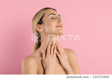 Young blonde woman tilts head back and touches her neck with hands Young blonde woman tilts head back and touches her neck with hands 139725665