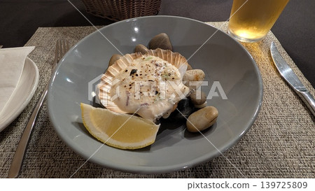 Scallops gratin in a shell dish and beer on a table Scallops gratin in a shell dish and beer on a table 139725809