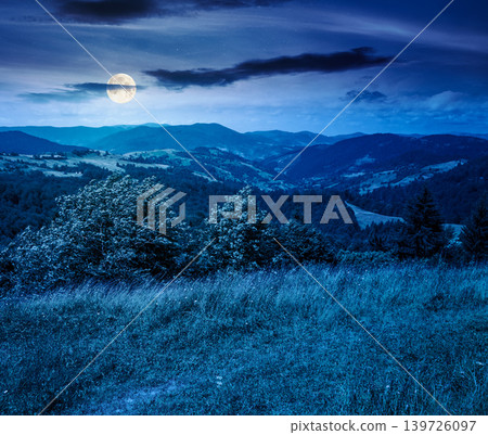 mysterious field on hillside in mountains near village at night. full moon over carpathian mountain landscape in summer. countryside view of alpine fields and rolling hills. cloudy sky mysterious field on hillside in mountains near village at night. full moon over carpathian mountain landscape in summer. countryside view of alpine fields and rolling hills. cloudy sky 139726097