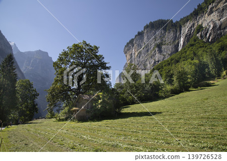 Lauterbrunnen valley landscape with traditional swiss cabin and waterfalls Lauterbrunnen valley landscape with traditional swiss cabin and waterfalls 139726528