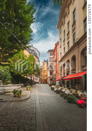 Wide cobblestone lane with trees and cafe awning in Gamla Stan, Stockholm Wide cobblestone lane with trees and cafe awning in Gamla Stan, Stockholm 139726574