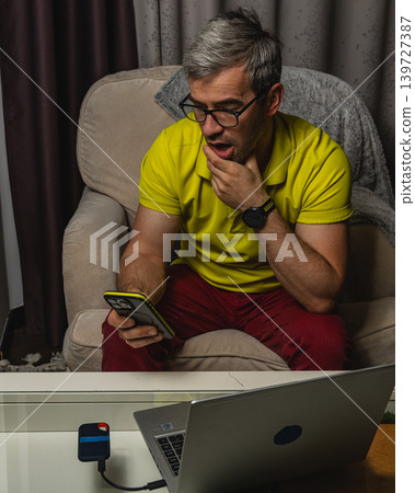 Freelancer using smartphone beside laptop at home Freelancer using smartphone beside laptop at home 139727387