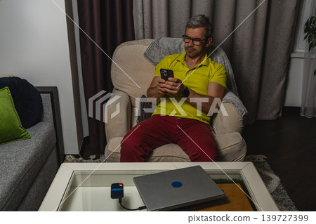 Man relaxing with smartphone after remote work Man relaxing with smartphone after remote work 139727399