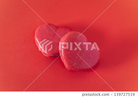 Pink heart shaped french macarons on a red background. Concept for Valentine's day. Pink heart shaped french macarons on a red background. Concept for Valentine's day. 139727519