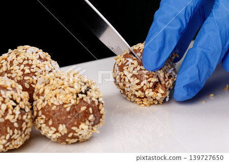 Beautiful candies with sesame seeds on a white plate on a black background Beautiful candies with sesame seeds on a white plate on a black background 139727650