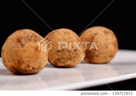 Beautiful candy truffle on a white plate on a black background Beautiful candy truffle on a white plate on a black background 139727651
