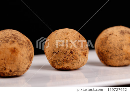 Beautiful candy truffle on a white plate on a black background Beautiful candy truffle on a white plate on a black background 139727652