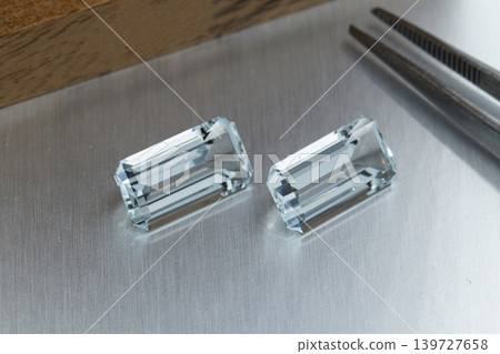 macro mineral faceted stone aquamarine with tweezers on a gray background macro mineral faceted stone aquamarine with tweezers on a gray background 139727658