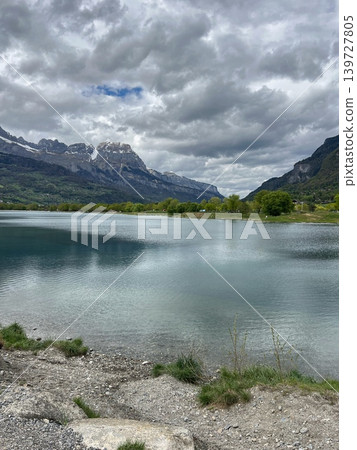 Scenic view of a tranquil lake surrounded by mountains and lush greenery Scenic view of a tranquil lake surrounded by mountains and lush greenery 139727805