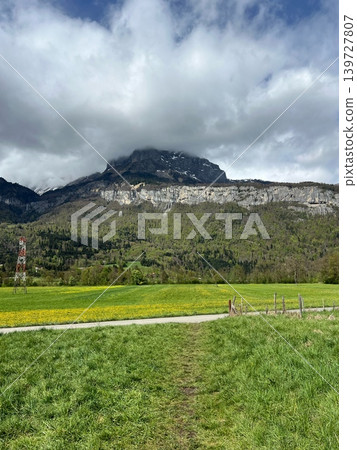Scenic view of a mountain landscape with lush green fields and cloudy Scenic view of a mountain landscape with lush green fields and cloudy 139727807