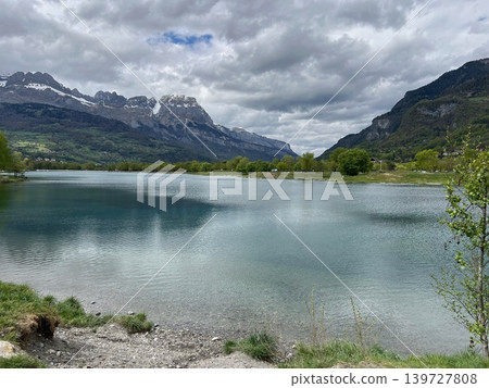 Scenic view of a tranquil lake surrounded by mountains and lush greenery Scenic view of a tranquil lake surrounded by mountains and lush greenery 139727808