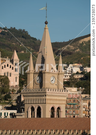 Historic Messina Cathedral bell tower with tall spire and flag rising above city rooftops in Sicily, Italy 139728073