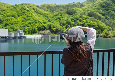 A woman photographs the Yamba Dam in early summer. A woman photographs the Yamba Dam in early summer. 139728089